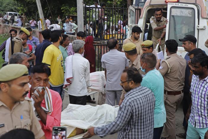Relatives and volunteers carry bodies on stretchers at the Sikandrarao hospital in Hathras district in northern India on Tuesday. A stampede among thousands of people at a religious gathering killed more than 120 and left scores injured, officials said.<br>