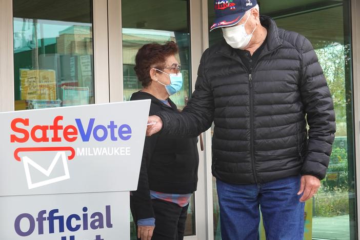 Wisconsin residents deposit mail ballots in a drop box outside of a library in Milwaukee on Oct. 20, 2020.