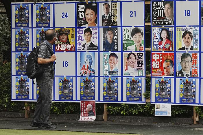 A person looks at an election poster board for Tokyo gubernatorial election Monday, July 1, 2024, in Tokyo. Tokyo elects a new governor on Sunday but residents say personal publicity stunts have overtaken serious campaigning — there are nearly nude women in suggestive poses, pets, an AI character and a man practicing his golf swing.