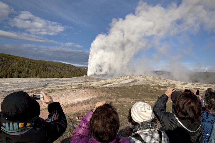 Tourists are seen photographing an eruption of Old Faithful at Yellowstone National Park in this 2011 file photo. On Thursday, a man was killed in an exchange of gunfire with law enforcement park rangers after he was reported to have a weapon and issuing threats, according to the National Park Service.