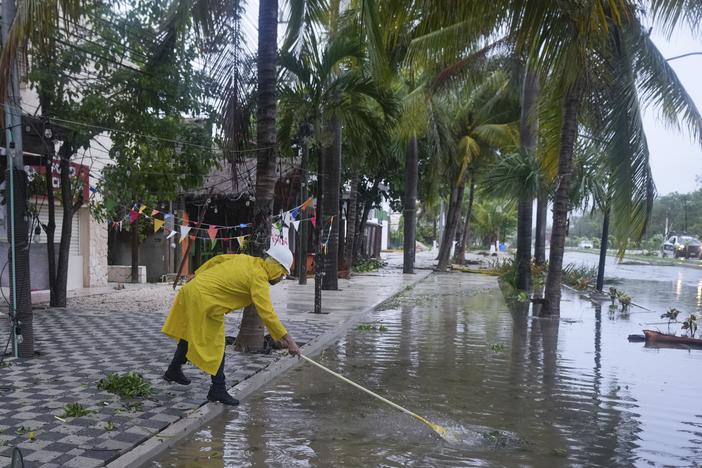 A man unclogs a drain in the aftermath of Hurricane Beryl, in Tulum, Mexico, on Friday.