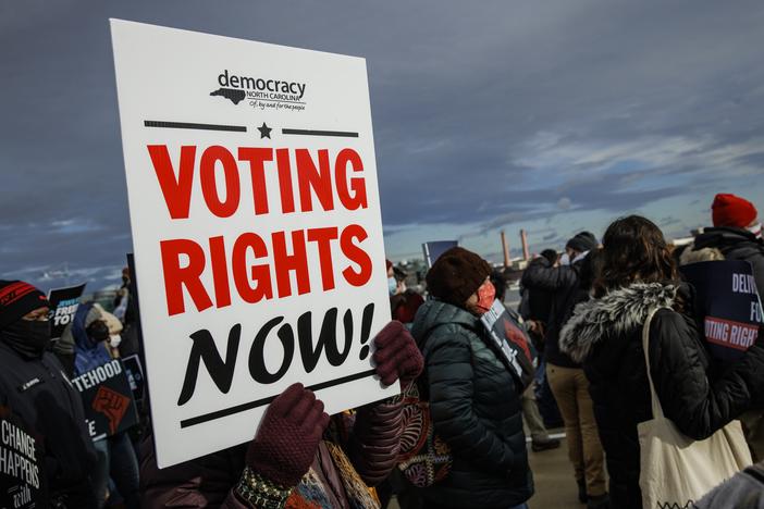 A person holds a sign that says "VOTING RIGHTS NOW" during a peace walk in Washington, D.C., on Martin Luther King Jr. Day in 2022.