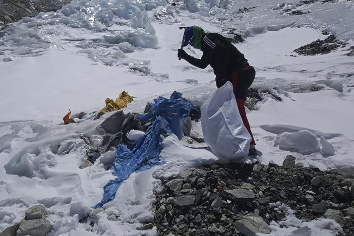 A member of a Nepal government-funded team uses a spade to remove frozen trash on Mount Everest in Nepal in 2021. In the seven decades since Mount Everest was first conquered, thousands of climbers have scaled the peak, and many have left behind more than just their footprints.