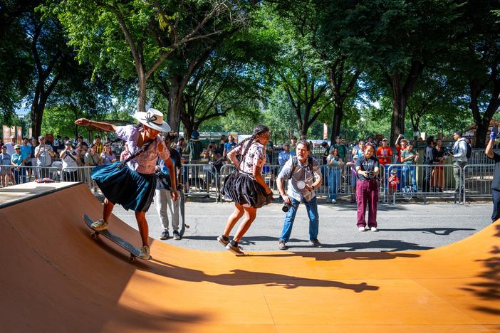 Bolivian women skateboarders — wearing traditional garb — demonstrate their skills on the half pipe. 