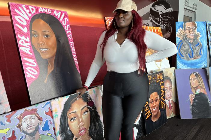 Zarinah Lomax stands beside portraits she commissioned, mostly of young people who died from gunfire. “The purpose is not to make people cry,” Lomax says. “It is for families and for people who have gone through this to know that they are not forgotten.” 