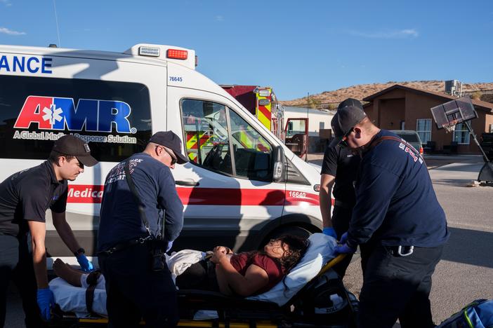 Sunland Park Fire Department firefighters and police officers roll a migrant woman, who was suffering from heat-related illness, on a gurney to be loaded into an ambulance in a residential area in Sunland Park, N.M., on Friday, June 28, 2024.