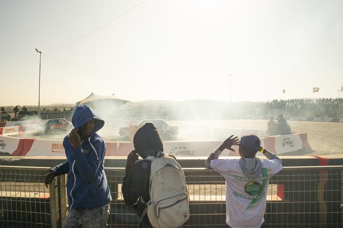 Three young spectators cover their faces from rubber debris and smoke at the spinning field, at Wheelz N Smoke arena, on July 7, in Johannesburg, South Africa.