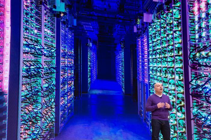 Google Vice President Majd Bakar speaks on-stage during an annual conference in San Francisco with the back drop of a massive data center.