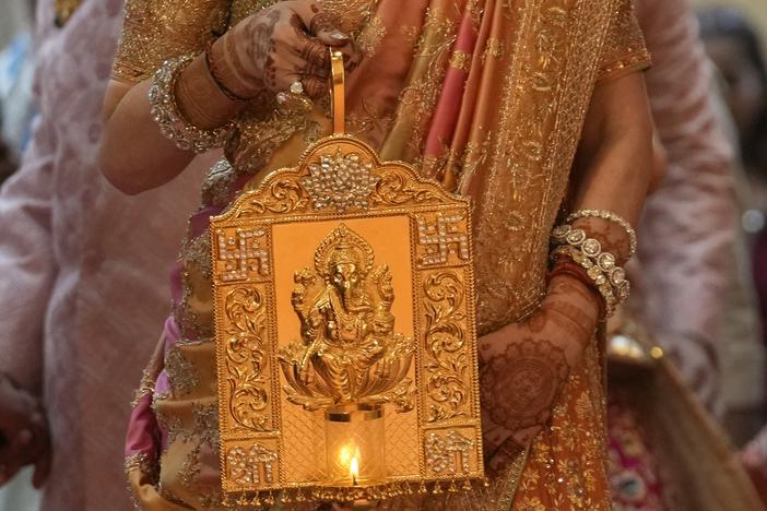 Nita Ambani, wife of Asia's richest man, Mukesh Ambani, arrives holding a lamp with an image of elephant-headed Hindu god Ganesha, for the wedding of their youngest son, Anant Ambani in Mumbai on Friday.