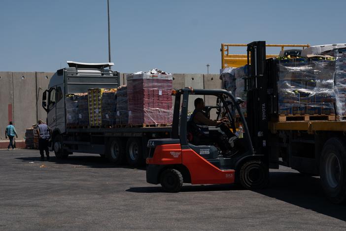A forklift driver loads a truck with food on the Israeli side of the Kerem Shalom border crossing with southern Gaza on Wednesday. Israel says food is going into southern Gaza daily but is piling up on the Gaza side because the United Nations and aid groups aren't distributing it in a timely fashion. The U.N. says Israeli military operations and other war-related obstacles hamper its efforts.