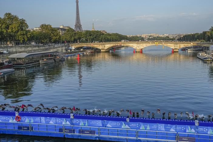 Athletes dive into the Seine River from the Alexander III bridge on the start of the first leg of the women's triathlon test event for the 2024 Paris Olympics in Paris in August 2023.