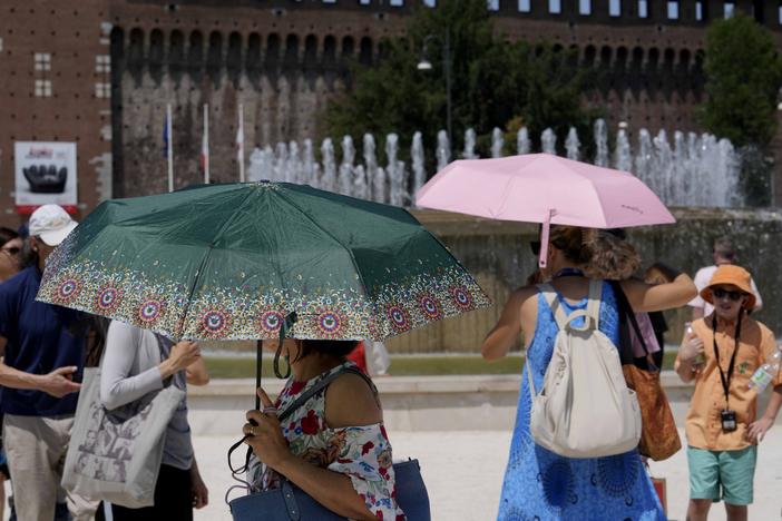 Tourists shelter from the sun in front of the Sforzesco Castle in Milan, Italy, on Tuesday. Weather alerts, forest fires, melting pavement in cities: A sizzling heat wave has sent temperatures in parts of central and southern Europe soaring toward 104 degrees Fahrenheit (40 degrees Celsius) in some places.