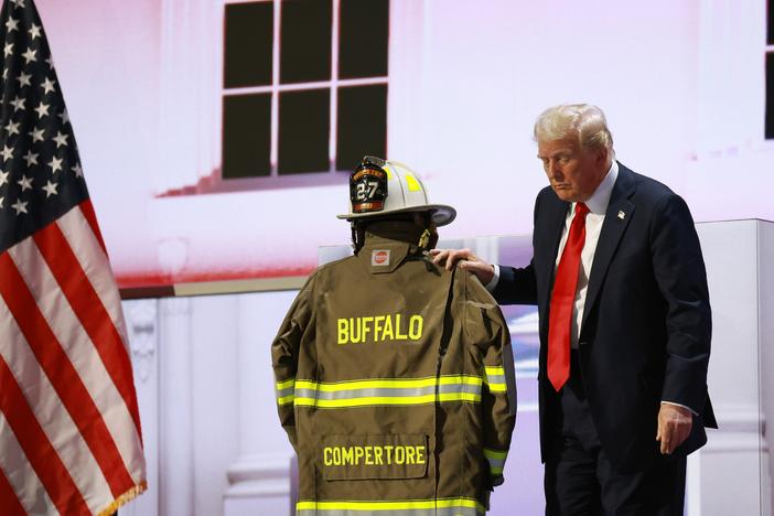 Republican presidential nominee, former President Donald Trump, embraces the firefighter uniform of Corey Comperatore as he speaks on stage on the fourth day of the Republican National Convention in Milwaukee. 