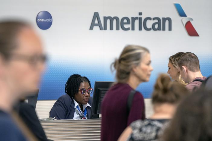 Travelers stand in line at an American Airlines counter at Reagan National Airport on Friday, July 19, 2024, in Arlington, Va. 
