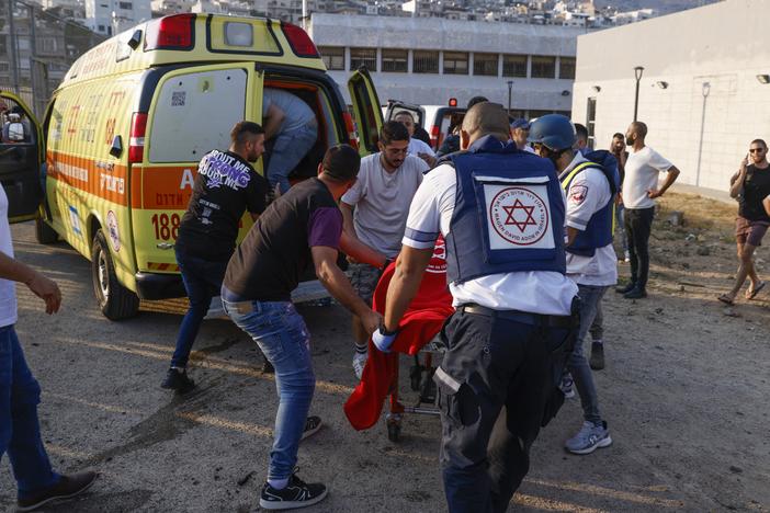 Israeli security forces and medics transport casualties along with local residents, at a site where a reported strike from Lebanon fell in Majdal Shams village in the Israeli-controlled Golan Heights area on Saturday.