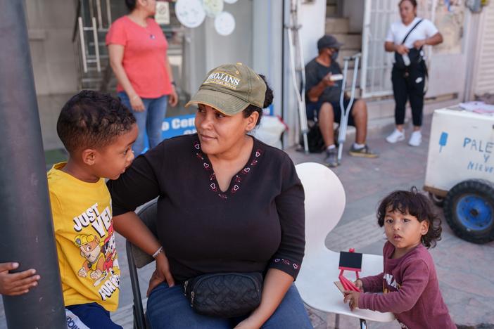 Yasmelin Velazquez, 35, from Venezuela sits with her sons (from left) Jordan and Jeremias Velazquez while selling souvenirs in Ciudad Juárez, Chihuahua state, Mexico, on Saturday. Velazquez is part of a growing number of migrants staying in Juárez and working while trying to get an appointment via the CBP One app.   