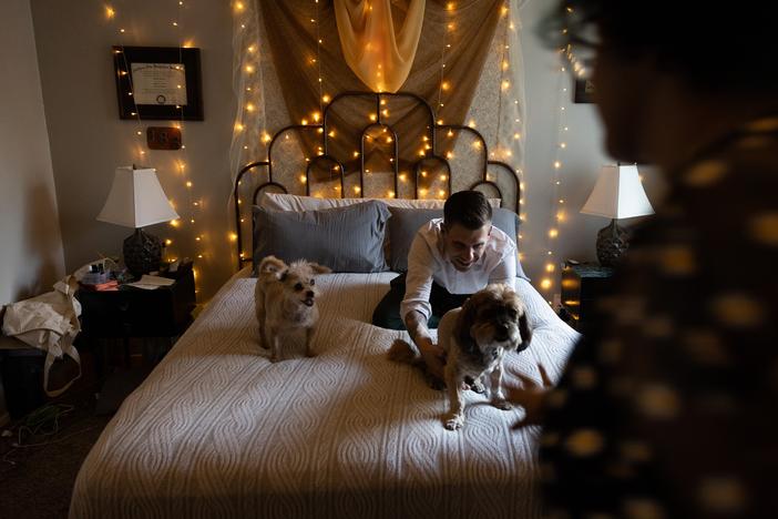 Thomas Guzowski, 40, greets his senior dogs as they climb onto the bed on July 18, in Redlands, California.