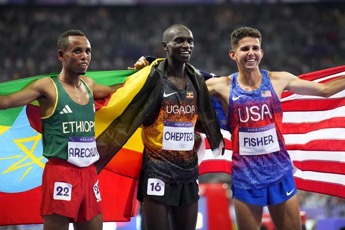 Gold medalist Joshua Cheptegei, of Uganda, poses with silver medalist Berihu Aregawi, of Ethiopia, left, and bronze medalist Grant Fisher, of the United States, after the men's 10,000-meter final at the 2024 Summer Olympics, Friday, in Saint-Denis, France.