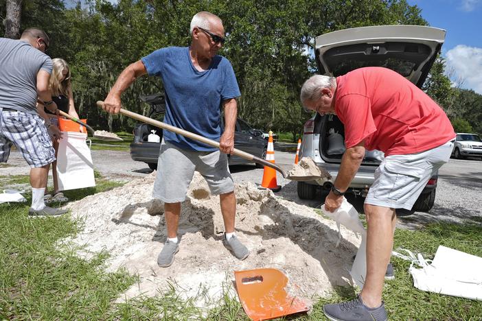 Roger Heim (right) and Terry Smith (second from right), both of Valrico, Fla., fill sandbags in preparation for the weekend storm at the Edward Medard Conservation Park in Plant City, Fla.