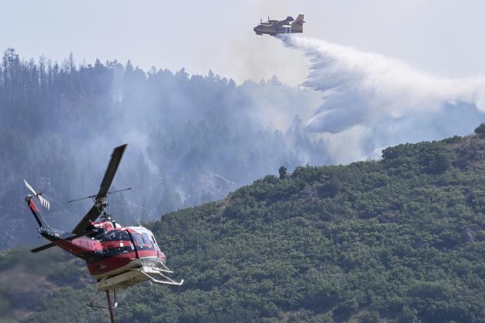 A CL 415 scooper, top, drops water on the Quarry Fire as a Firehawk helicopter maneuvers for a water drop Thursday, southwest of Littleton, Colo. 