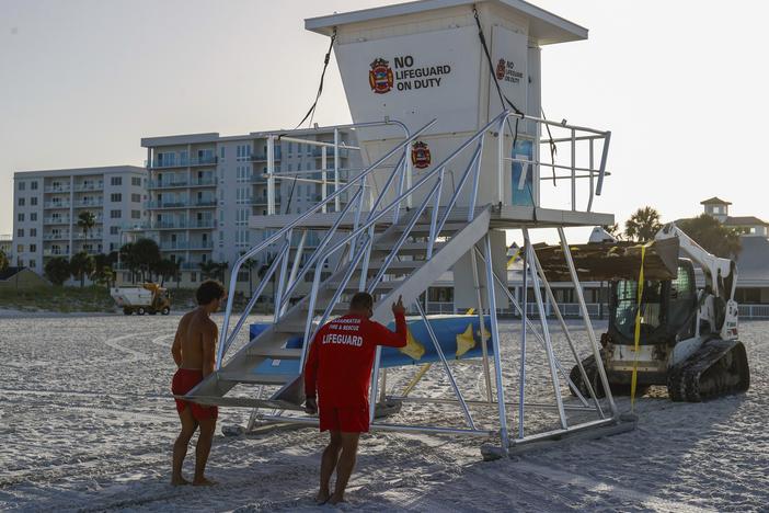 From left, Matthew Blowers and Patrick Brafford prepare to secure a lifeguard tower in preparation of potential storm at Clearwater Beach on Saturday, in Clearwater, Fla.