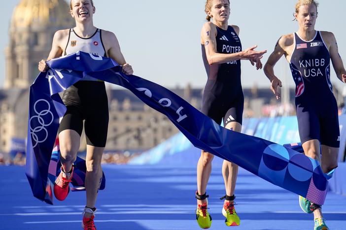 Germany's Laura Lindemann, left, celebrates after winning the gold medal next to silver medalist Great Britain's Beth Potter, center, and bronze medalist Taylor Knibb, of the U.S., right, at end of the mixed relay triathlon on Monday in Paris.