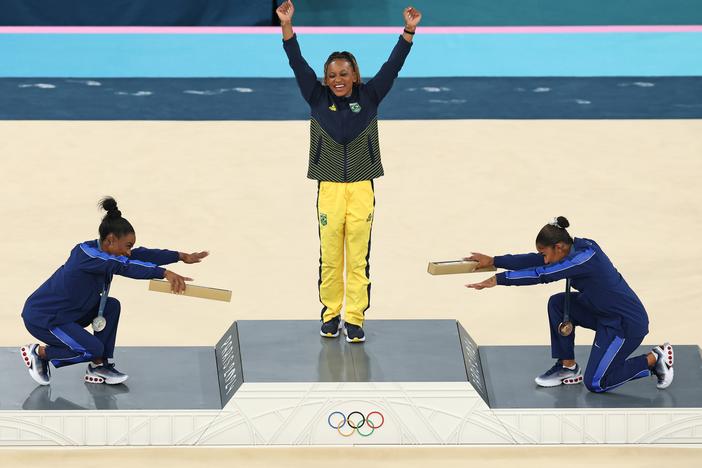 Gymnast Rebeca Andrade (center) of Brazil wins her first gold medal in Paris. Paying homage are silver medalist Simone Biles (left) and bronze medalist Jordan Chiles of the United States. 