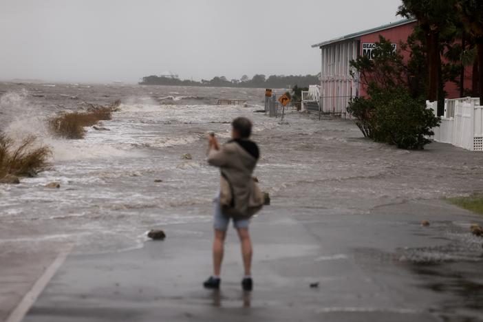 A person looks at a flooded street caused by the rain and storm surge from Hurricane Debby on Monday in Cedar Key, Fla. Hurricane Debby is now moving slowly over Georgia, bringing heavy rain storms and high winds along the coast.