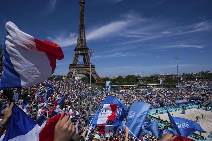 Supporters for France wave flags during the women's pool C beach volleyball match between Germany and France at Eiffel Tower Stadium on Sunday.