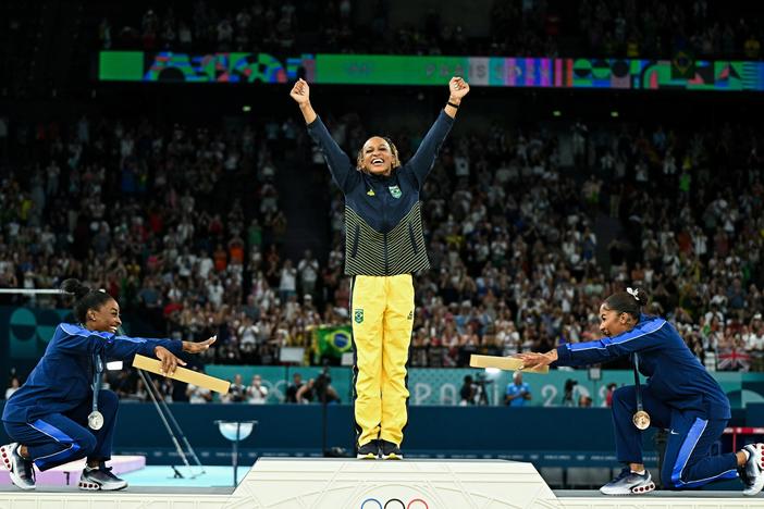 Simone Biles, left, joins teammate Jordan Chiles in pointing toward gold medalist Rebeca Andrade of Brazil. Biles won silver and Chiles bronze in the women's floor exercise at the Paris 2024 Olympic Games — the first time three Black athletes have shared the podium in Olympic gymnastics.