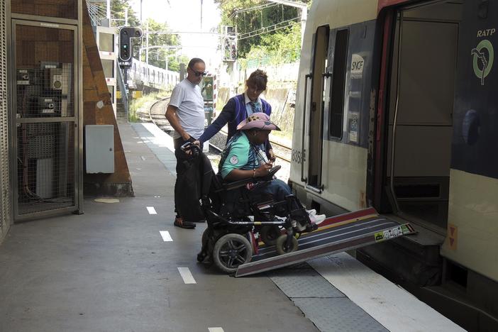 Ndieme Lame, a 57-year-old volunteer for the Paris 2024 Olympic and Paralympic Games navigates a ramp to join a RER train with the help of rail agents, during the 2024 Summer Olympics, on Wednesday in Paris, France. 