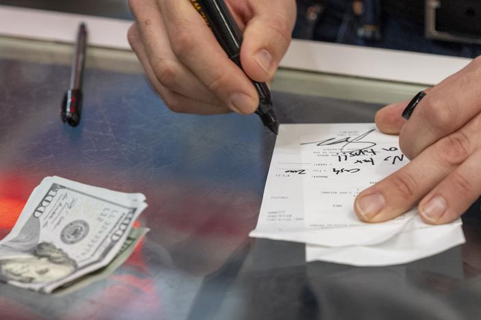 Republican vice presidential candidate Sen. JD Vance, R-Ohio, signs a check "no tax on tips!!" as he leaves $200 in cash for a gratuity at the Park Diner, in Waite Park, Minn., on July 28.