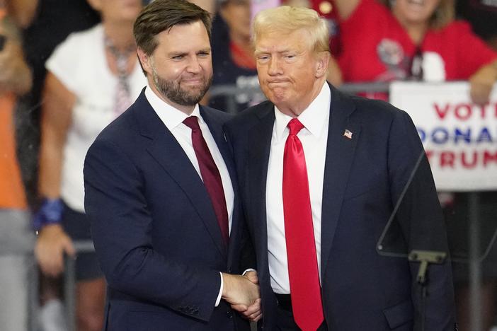 Former President Trump and his running mate, Sen. JD Vance of Ohio, shake hands at a campaign rally at Georgia State University in Atlanta, on Aug. 3, 2024. 