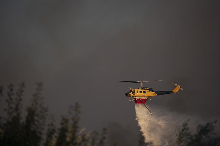 A helicopter drops water near Varnava village during a wildfire, north of Athens, Greece, on Sunday, with many regions of the country on high alert due to high temperatures and wind speeds.