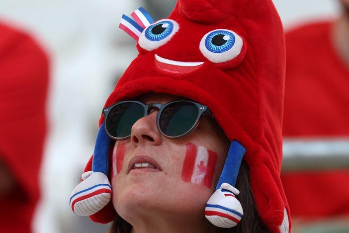 A Canada fan dons an Olympic mascot Phryge hat before the women's quarter-final football match between Canada and Germany during the Paris Olympics.