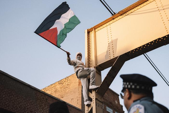 A Pro-Palestinian protester climbs a support beam near the United Center on Wednesday.