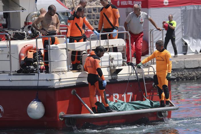Italian firefighter divers bring ashore the body of one of the victims of a shipwreck, in Porticello, Sicily, on Friday Aug. 23.