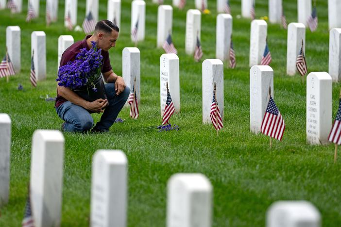 A man places flowers in front of headstones in Section 60, which mark the final resting place of service men and women at Arlington National Cemetery on May 27 in Arlington, Va. Originally known as Decoration Day, Memorial Day began after the Civil War to commemorate soldiers who died in that conflict and now honors all Americans who have sacrificed their lives in all wars. (Photo by Kent Nishimura/Getty Images)