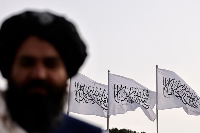 A Taliban fighter is pictured against the backdrop of Taliban flags installed at Kabul's international airport on September 11, 2021.