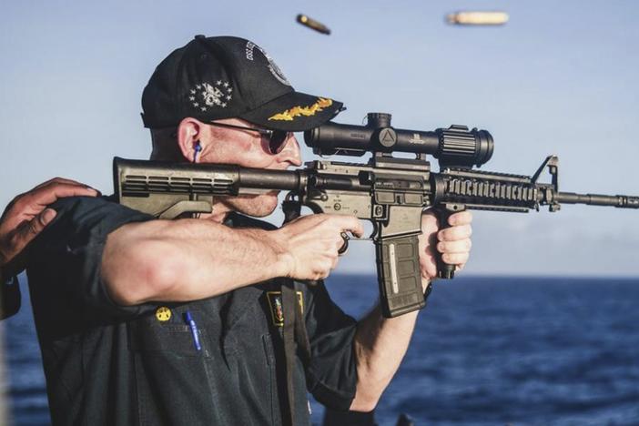 This undated photo, provided by <em>Stars and Stripes</em>, shows Cameron Yaste, commanding officer of the destroyer USS John McCain, firing a rifle with a backwards scope.