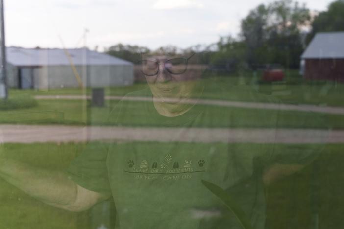 Cindie Haakenson is seen through a window of her home as the family farm is reflected before her on May 21 in Willow City, N.D. Despite a preference to remain at home, Cindie's husband, Sherwood Haakenson, needed to move to a 24-hour long-term care center.