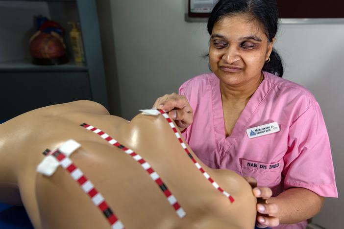 Meenakshi Gupta, who is blind, works as a "medical tactile examiner" to identify breast tumors. The mannequin is used in the training program for would-be examiners. The strips enable the examiners to identify and carefully examine each zone of the breast.