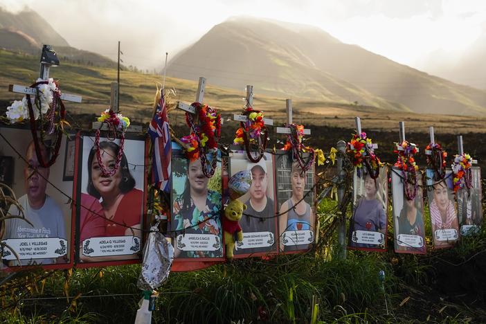 Photos of victims are displayed under white crosses at a memorial for victims of the August 2023 wildfire, above the Lahaina Bypass highway on Dec. 6, 2023 in Lahaina, Hawaii.