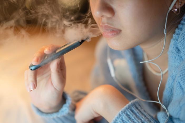 A young woman vapes an electronic cigarette. Some districts are installing high-tech vape detectors to alert school officials if students are using e-cigarettes.