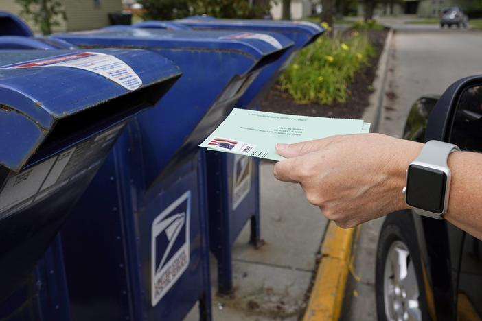 A person drops applications for mail-in-ballots into a mailbox in 2020 in Omaha, Neb.