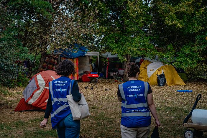 Lillian Risser, left, and Sophia Loveland, right, approach an encampment in Humboldt Park on Sept. 23 in Chicago. Risser and Loveland are outreach workers for Thresholds, a mental health care provider in Illinois that works to move people out of encampments into more permanent housing. 