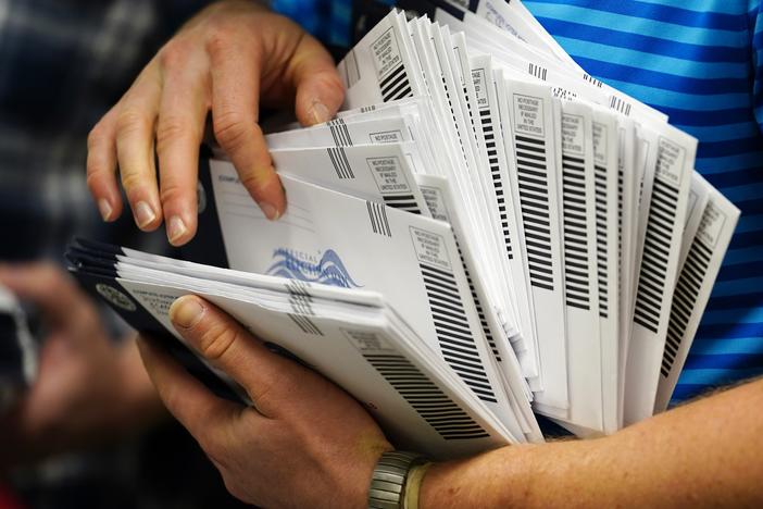 An election official organizes mail-in ballots to be sorted for the 2020 general election in West Chester, Pa.