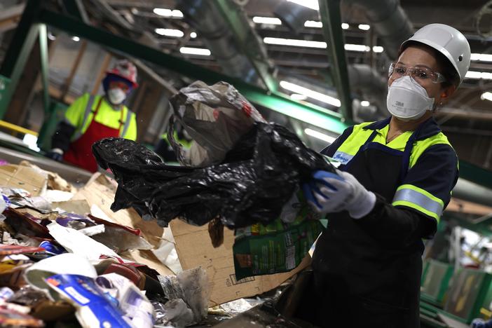 California is banning single-use plastic bags at grocery stores and other retailers, after an earlier ban was blamed for making the waste problem worse. Here, a worker pulls a plastic bag from a conveyor belt as she sorts through materials at a recycling center in San Francisco.