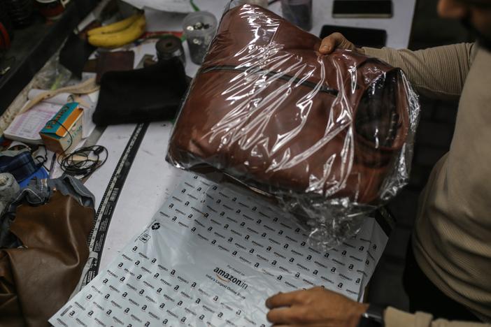 A worker packs a leather jacket in an Amazon India shipping bag at a workshop in the Dharavi area of Mumbai, India, on Jan. 5, 2022.