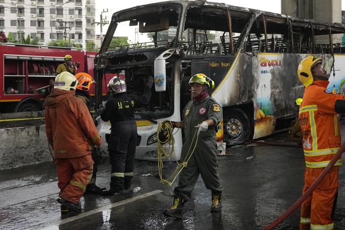 Rescuers work at the site of a bus that caught fire, carrying young students with their teachers, in suburban Bangkok on Tuesday.